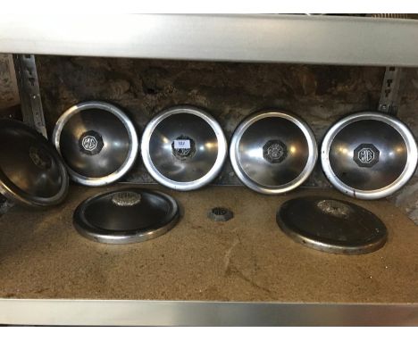 Seven vintage MG hub caps in chrome with one spare MG logo. Diameter 22cm 