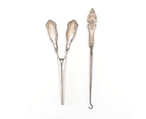 A silver handled button hook together with a silver handled glove stretcher. The button hook having a kings pattern to the ha