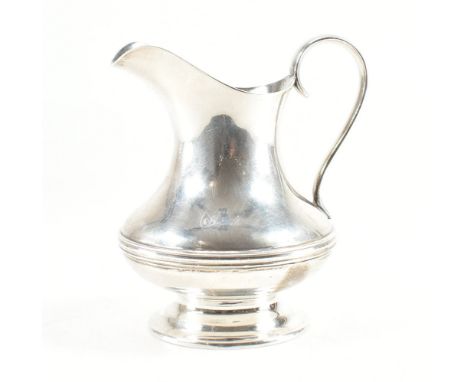 A hallmarked silver &amp; gilt milk jug. The jug raised on a flared plinth base &amp; squat form with banding to the body, sc