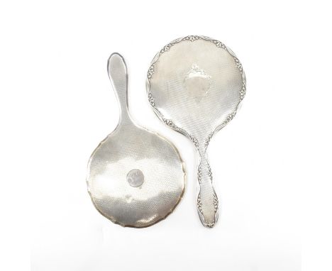 Two early to mid century hallmarked silver hand mirrors. First mirror having a moulded undulating edge with floral pattern to