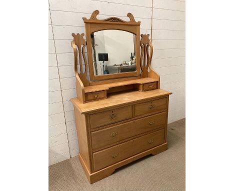 An antique pine dressing table with mirrored top with S shaped supports terminating with drawers 