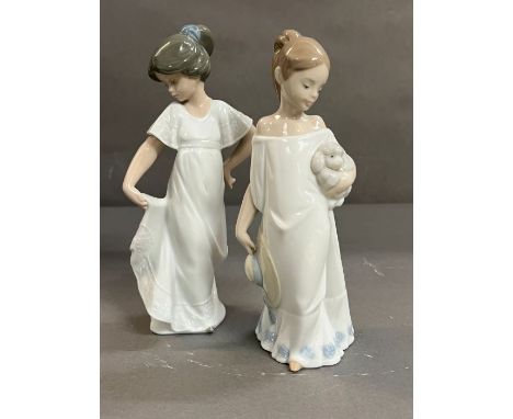 Two Nao figurines, one holding a dog and one holding her dress 