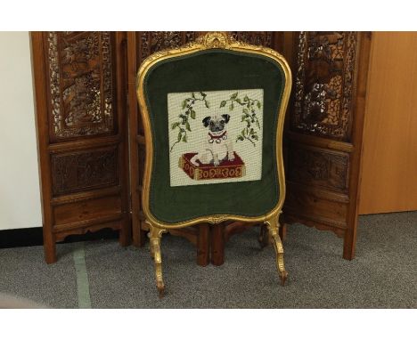 A tapestry firescreen, the tapestry depicts a pug dog seated on a pillow, with a green velvet and braid surround, in a gilt f