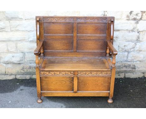 An Oak Monks Bench - with hinged lift top and decorative carving, approx 50 x 105 x 107 cms.