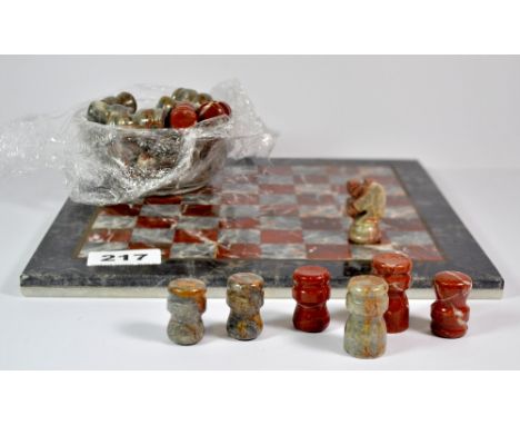 A polished stone chess board and pieces, 25 x 25cm.