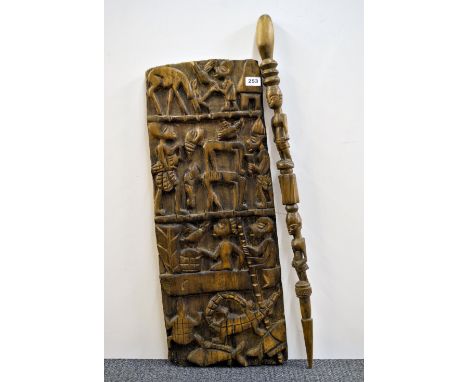 A carved wooden tribal panel and a walking stick.