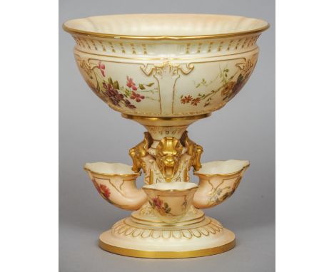 A Royal Worcester porcelain centrepiece
The central bowl supported on mystical beast mask headed cornucopia, standing on a sp