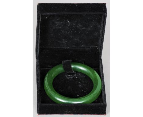 A Chinese carved green jade bangle
Of typical form, in fitted case.  9 cm diameter. CONDITION REPORTS: Generally in good cond