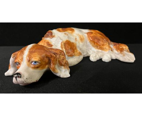 An early 20th  century German bisque model, of a King Charles Spaniel, reclining, 22cm wide, c.1910 