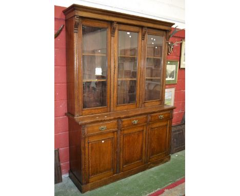 An early 20th century oak display cabinet, moulded cornice, three glazed doors to top, projecting base, three short drawers o