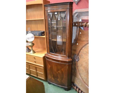 A floor standing bow front corner cabinet, dentil cornice, astragal glzed door to top, projecting base, single panel door, og