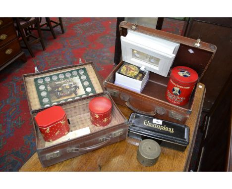 A leather suit case, another smaller;  a wall display cabinet;  coasters decorated with birds; a walking stick, another etc (