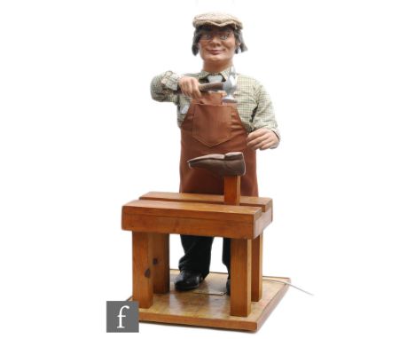 A post 1950s shop automaton display of a cobbler mending a shoe and wearing a flat cap, apron chequered shirt and tie,&nbsp;b