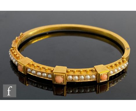 An early 20th Century gold child's hinged bangle set with split seed pearl and coral, weight 11g, internal diameter 50mm, unm