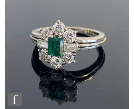 An 18ct white gold emerald and diamond cluster ring, central emerald flanked by baguette cut diamond and six further brillian