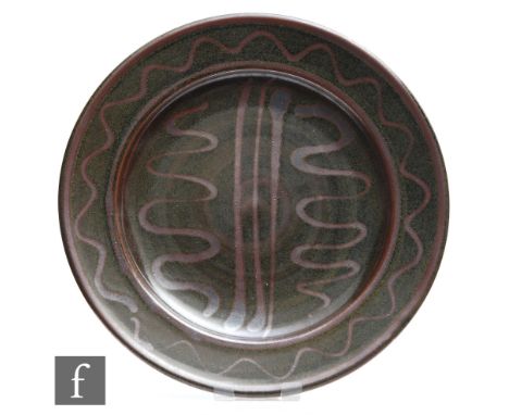 A Winchcombe Pottery dish decorated with brown wavy and straight lines in an oxide glaze against a speckled brown ground, att