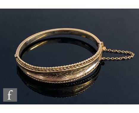 A 9ct hallmarked hinged bangle with part foliate engraved decoration within pierced borders, total weight 14g, Birmingham 197