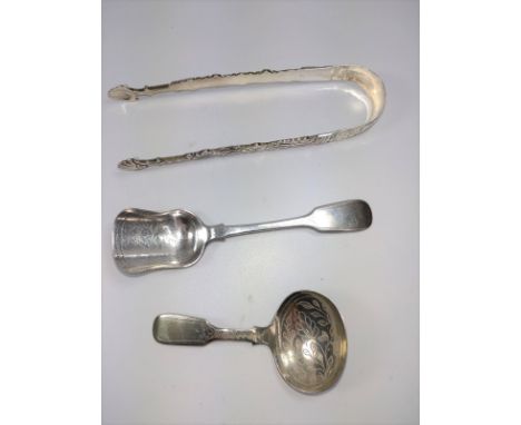 A pair of decorative sugar nips together with a possibly imported plated shovel spoon and a caddy spoon. 