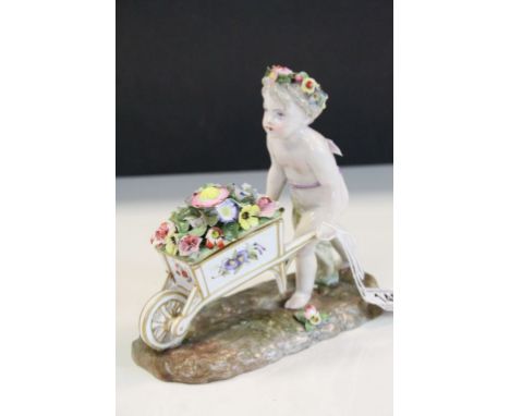 Meissen style ceramic figurine of a Garland Flower wearing Cherub pushing a wheelbarrow of Flowers with crossed sword mark to