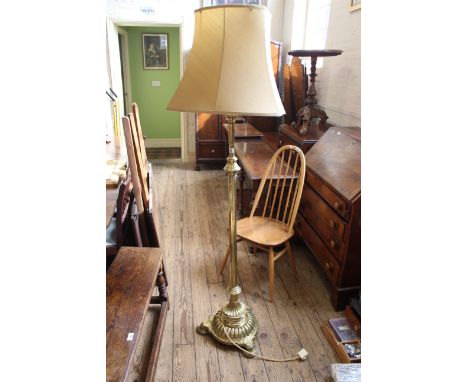 An early 20th Century brass standard lamp on a round fluted base with shaped feet