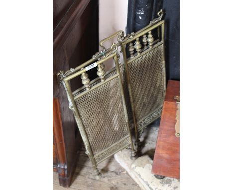 A brass fireguard of three folding sections with a brass mesh and turnings above