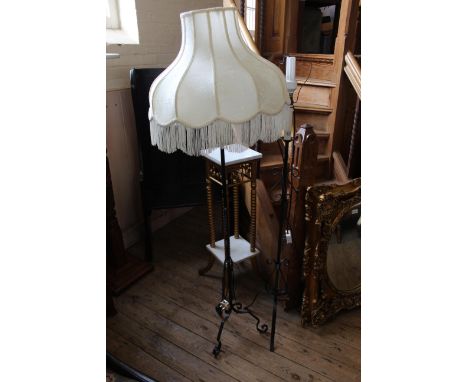 Two wrought iron standard lamps on tripod feet
