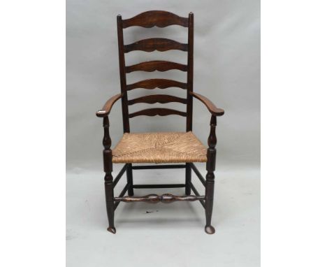 A 19TH CENTURY COUNTRY VERNACULAR LADDER BACK ARMCHAIR with rush seat, 111cm high 