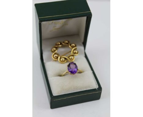 A LARGE AMETHYST SET LADY'S DRESS RING, stamped 10k and a gold coloured metal circular LAPEL BROOCH of ball design held withi