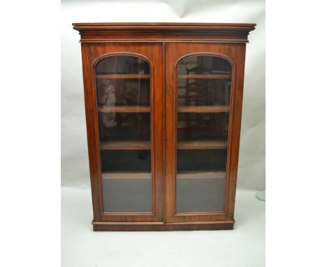 A LATE 19TH CENTURY MAHOGANY TWO-DOOR BOOKCASE with plain arch topped glazed panels, on a short plain plinth base, 161cm x 12