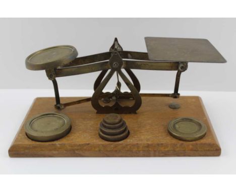 A SET OF EARLY 20TH CENTURY BRASS POSTAL SCALES, an oak base with a graduated set of weights from 1/4oz to 8oz, the frame sta