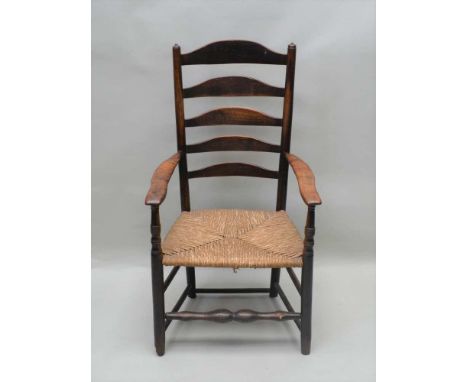 AN EARLY 19TH CENTURY VERNACULAR COUNTRY LADDER BACKED ARMCHAIR with rush seat, 107cm high 