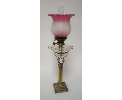 A Victorian oil lamp, having a later purple tinted frilled glass shade, above a clear glass font, on a brass corinthian colum