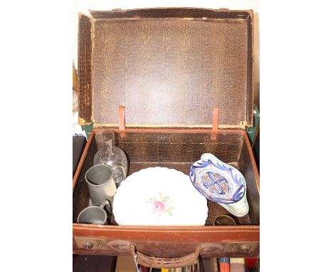 A tan leather vintage suitcase containing a small collection of various items to include two pewter tankards, an etched glass