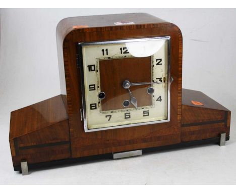 An Art Deco walnut and crossbanded mantel clock, having a square silvered dial with Arabic numerals and chiming movement, w.3
