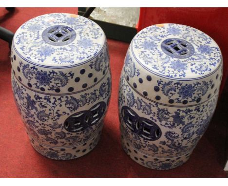 A pair of reproduction Chinese style blue and white ceramic garden seats, of barrel shape, having pierced and floral decorati