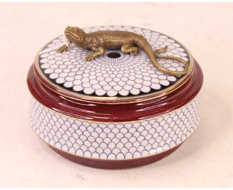 A modern jar and cover, of square circular form, on a deep red ground with fish-scale type decoration, the cover surmounted b