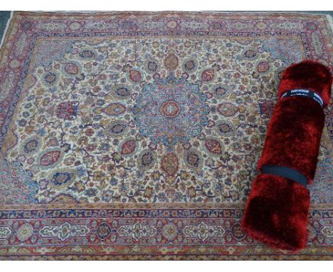 A modern tufted wool rug &amp; a vintage-style tassel ended woollen rug, floral patterned on a cream red ground