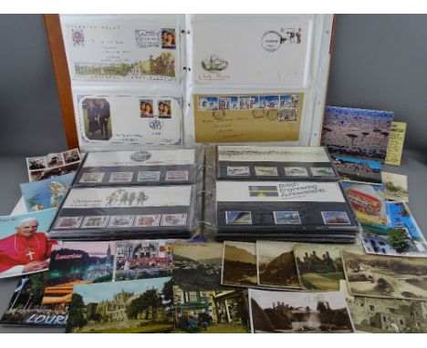 A two-album collection of first day covers, commemorative &amp; other Mint stamps with a small collection of vintage postcard