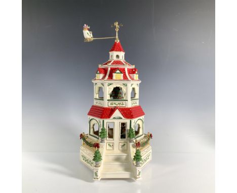 Stunning Victorian centerpiece featuring a three-story home with Santa in his sleigh circling above. The red roofed home is d