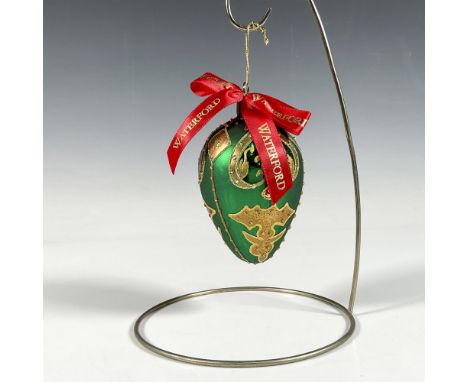 Handcrafted ornament adorned with gold decorative elements that include holly leaves and a stylized fleur de lis crown. The s