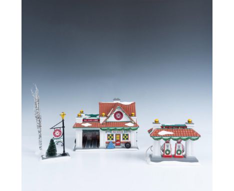 A beautiful set of three figurines that includes a white brick gas station blanketed in snow with glowing windows, a matching