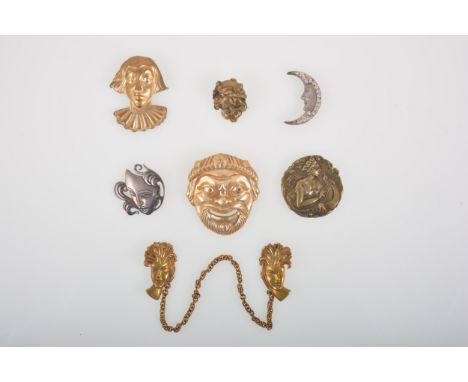 Fifteen Art Nouveau and Art Deco gilt metal mask brooches and earrings, a pair of mask head pins with cloak chain between, a 