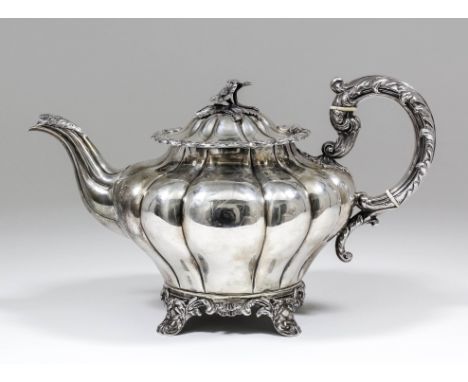 A William IV silver teapot with squat lobed circular body, conforming lid with cast floral finial, within bold leaf scroll mo