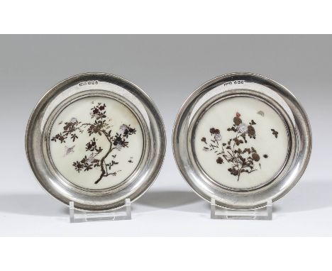 A pair of late Victorian silver circular coasters, each inset with shibayama panels inlaid with flowering branches, birds and
