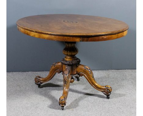A Victorian walnut oval breakfast table, the centre inlaid with oval floral motif, on turned and reeded central column and qu