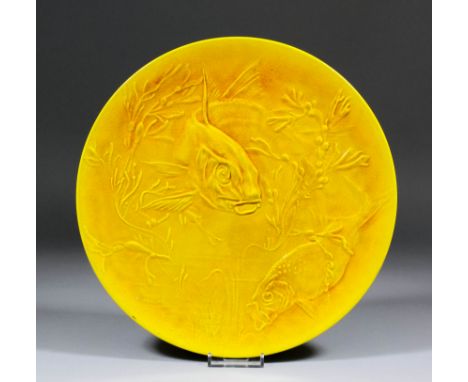 A late 19th Century Burmantofts "Faience" yellow glazed circular wall plaque moulded in relief with fish amongst weeds and de
