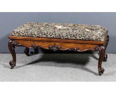 A Victorian walnut rectangular stool, the lifting lid upholstered in tapestry (damaged) with shaped and carved scroll apron a