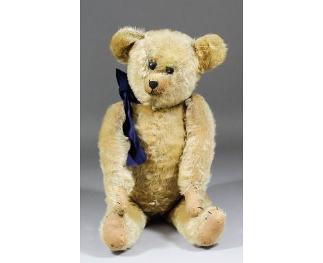 An early 20th Century American blond mohair teddy bear with black button eyes and hump, 21.25ins high (circa 1910)