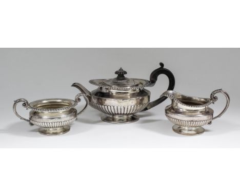 A George IV and William IV silver Harlequin three piece tea service of circular squat form with gadroon mounts, part reeded b