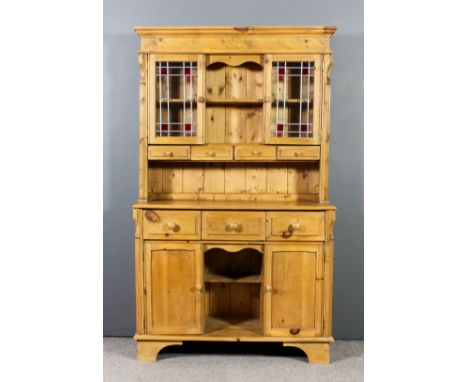 A stripped pine dresser of Victorian design, the upper part with moulded cornice, fitted central open shelf flanked by shelve